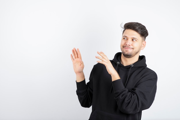 Imagem de jovem com capuz preto em pé e posando