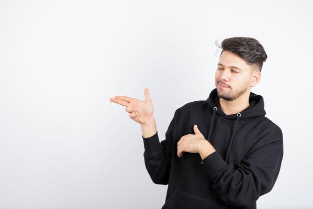 Imagem de jovem com capuz preto em pé e posando