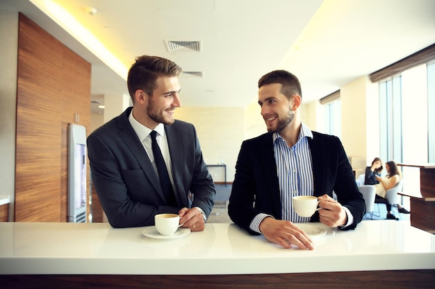 Imagem de jovem empresário com uma xícara de café se comunicando com seu colega