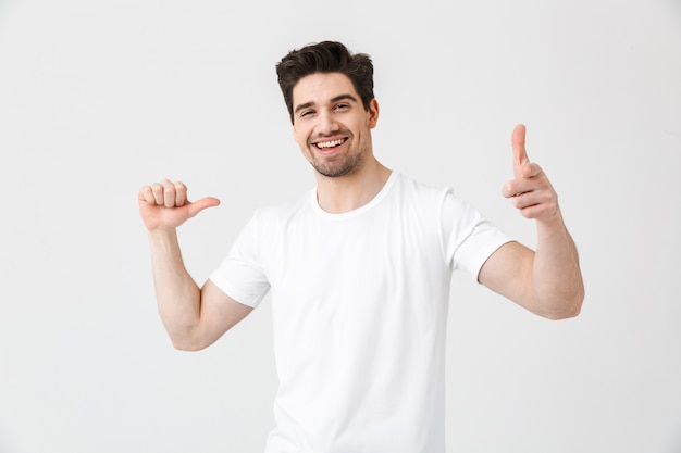 Imagem de jovem feliz animado posando isolado na parede branca, apontando para si mesmo e você.