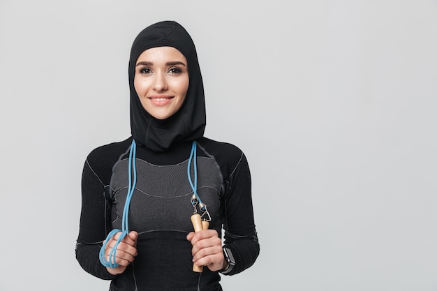 Imagem de jovem mulher fitness muçulmano posando isolado fazer exercícios com pular corda.