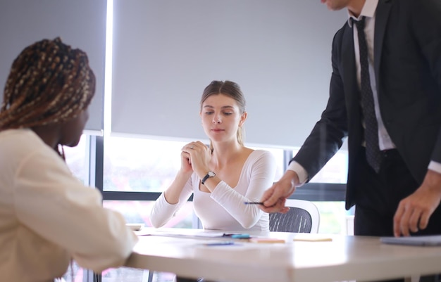 Imagem de jovens empresários a discutir um documento em dados de papelada sobre a mesa numa reunião