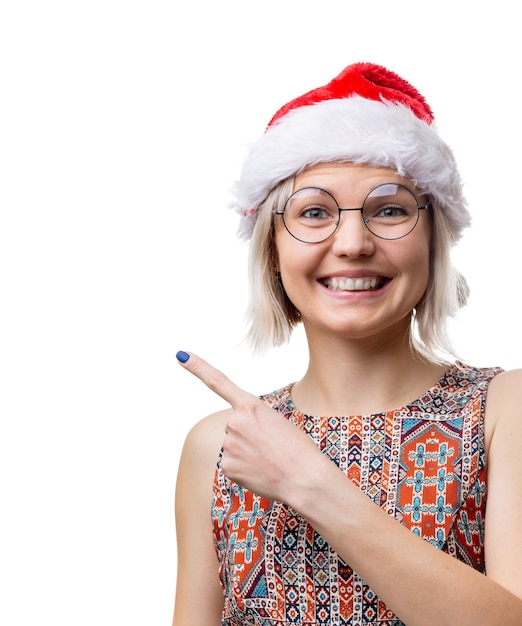 Imagem de loira feliz de óculos e boné de Papai Noel mostrando o dedo no espaço vazio