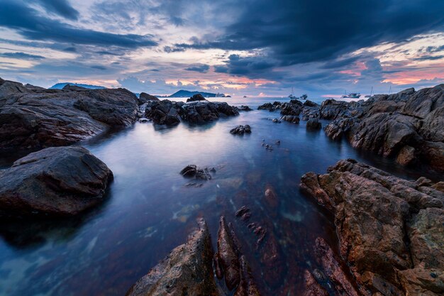 Imagem de longa exposição de paisagem dramática do céu com pedra no cenário por do sol