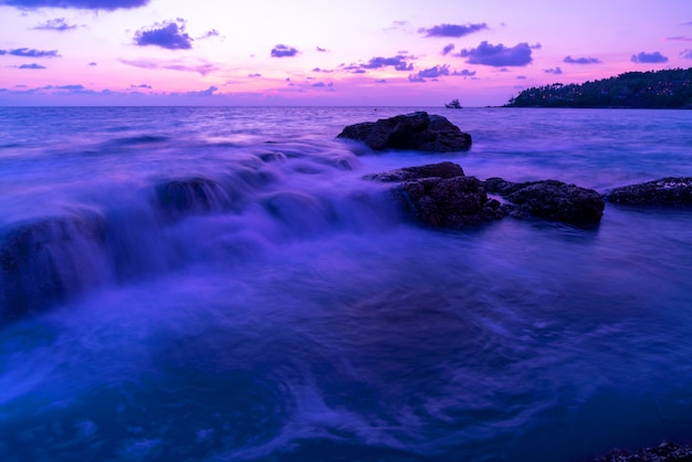 Imagem de longa exposição de vista dramática do cenário do nascer do sol ou do pôr do sol do seascape do céu Natureza clara bonita e ondas quebrando em rochas.