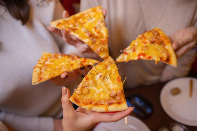 Imagem de mãos de amigos adolescentes pegando fatias de pizza