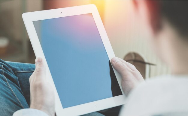 Imagem de maquete da mão de uma mulher segurando o tablet pc branco com tela branca em branco em casa