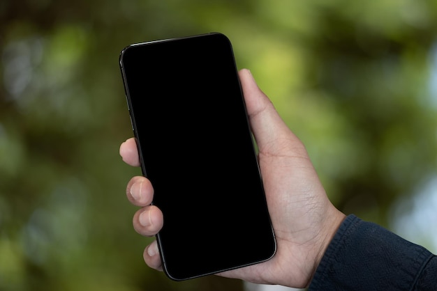 Imagem de maquete da mão segurando o celular branco com fundo verde branco em branco da natureza