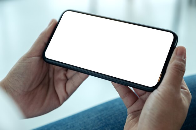 Imagem de maquete das mãos de uma mulher segurando um telefone celular preto com a tela em branco na horizontal