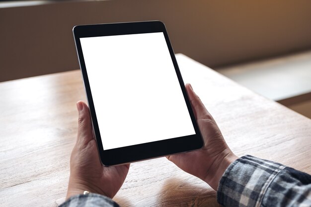 Imagem de maquete de mãos segurando o pc tablet preto com tela de desktop branco em branco