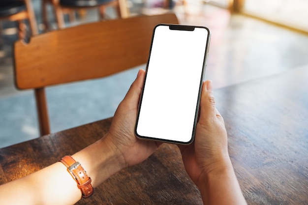 Imagem de maquete de mãos segurando um celular preto com uma tela em branco