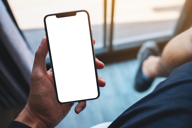 Imagem de maquete de um homem segurando o celular com tela branca em branco no café