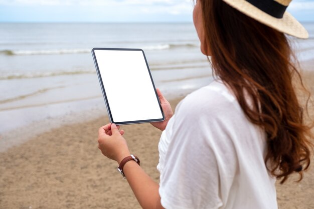 Imagem de maquete de um woamn segurando um tablet pc preto com uma tela em branco à beira-mar