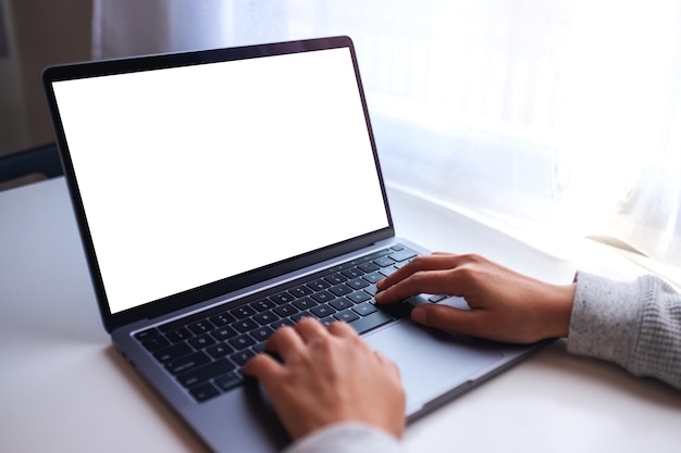 Imagem de maquete de uma empresária usando e digitando no teclado do computador portátil com tela branca em branco na mesa