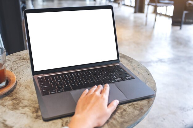 Imagem de maquete de uma mão tocando no touchpad do computador portátil com tela branca em branco na mesa