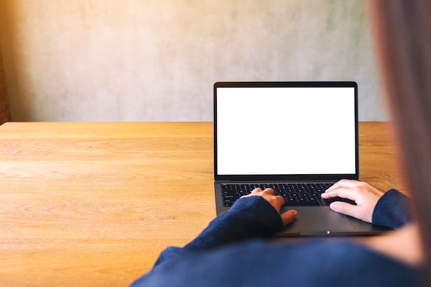 Imagem de maquete de uma mão usando e tocando no touchpad do laptop com a tela do desktop em branco na mesa de madeira