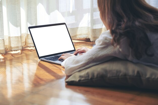 Imagem de maquete de uma mulher digitando em um laptop com uma tela em branco enquanto está deitada no chão sentindo-se relaxada