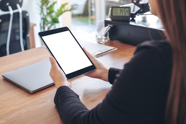 Imagem de maquete de uma mulher segurando e usando um tablet pc preto com uma tela de desktop em branco