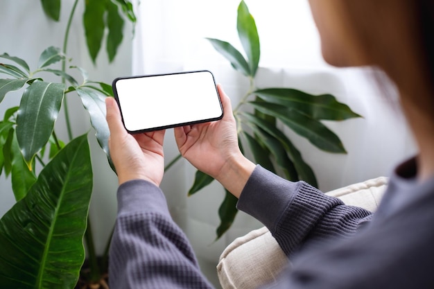 Imagem de maquete de uma mulher segurando o celular com tela em branco do desktop em casa