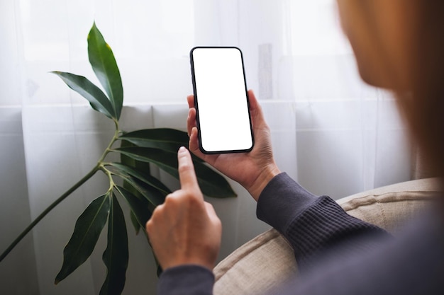 Imagem de maquete de uma mulher segurando o celular com tela em branco do desktop em casa