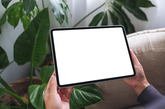 Imagem de maquete de uma mulher segurando o tablet digital com tela branca em branco do desktop em casa