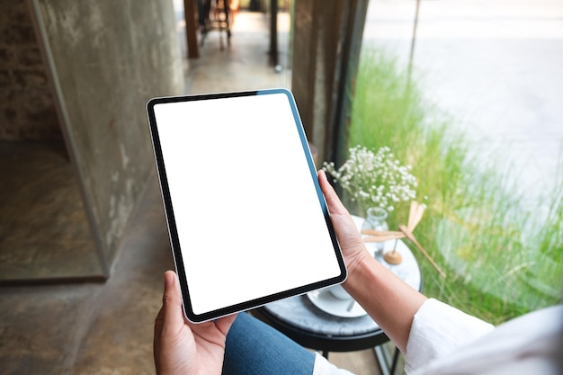 Imagem de maquete de uma mulher segurando o tablet digital com tela branca em branco do desktop no café