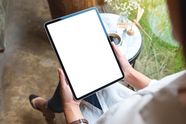 Imagem de maquete de uma mulher segurando o tablet digital com tela branca em branco do desktop no café