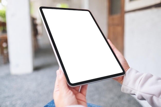 Imagem de maquete de uma mulher segurando um tablet digital com tela de desktop branca em branco ao ar livre