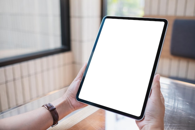 Imagem de maquete de uma mulher segurando um tablet digital com tela de desktop branca em branco em um café