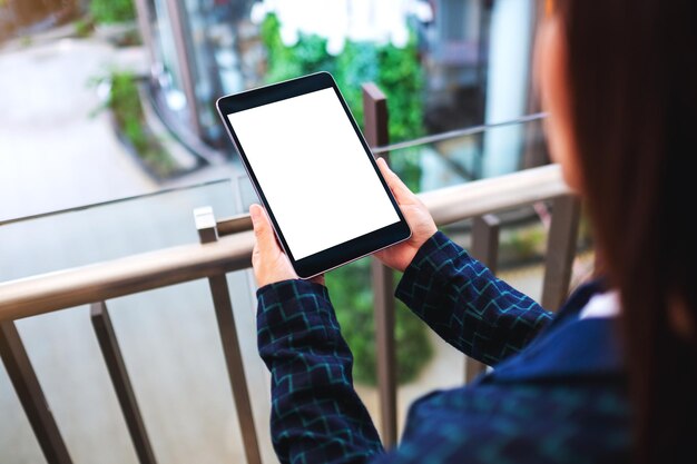 Imagem de maquete de uma mulher segurando um tablet pc preto com a tela do desktop em branco dentro de casa