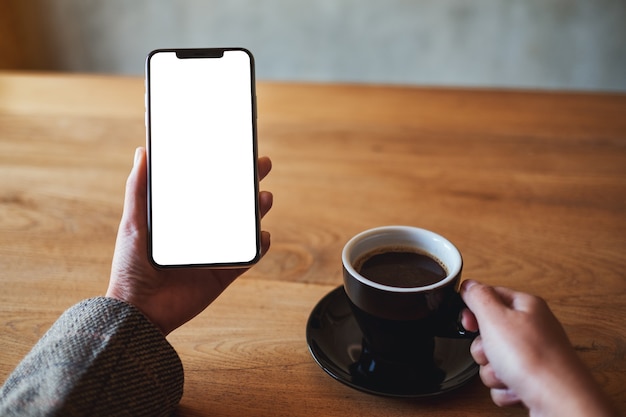 Imagem de maquete de uma mulher segurando um telefone celular com uma tela em branco enquanto bebe café