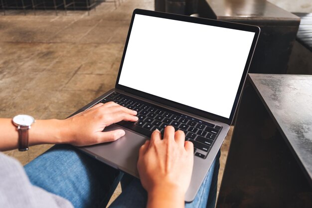 Imagem de maquete de uma mulher usando e digitando no laptop com tela branca em branco no café