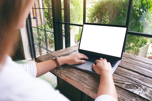 Imagem de maquete de uma mulher usando e digitando no teclado do laptop com a tela do desktop em branco na mesa de madeira