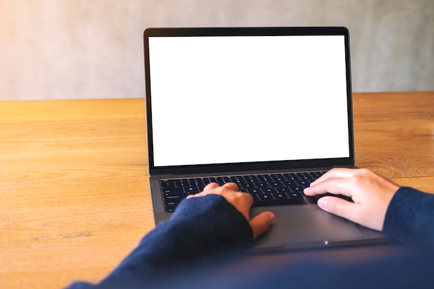 Imagem de maquete de uma mulher usando e digitando no teclado do laptop com a tela do desktop em branco na mesa de madeira