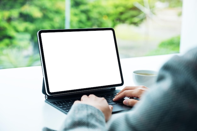 Imagem de maquete de uma mulher usando e digitando no teclado do tablet com tela branca em branco como um computador pc no escritório