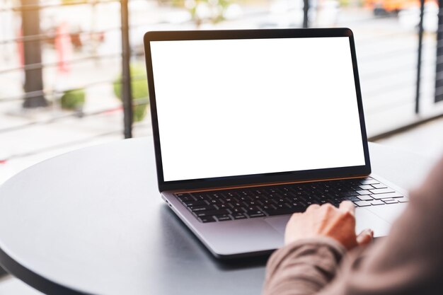 Imagem de maquete de uma mulher usando e tocando no touchpad do laptop com tela branca em branco na mesa