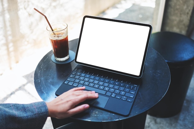 Imagem de maquete de uma mulher usando e tocando no touchpad do tablet com a tela em branco da área de trabalho como um PC com uma xícara de café na mesa