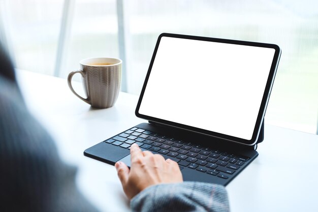 Imagem de maquete de uma mulher usando e tocando no touchpad do tablet com tela de desktop em branco como pc, xícara de café na mesa