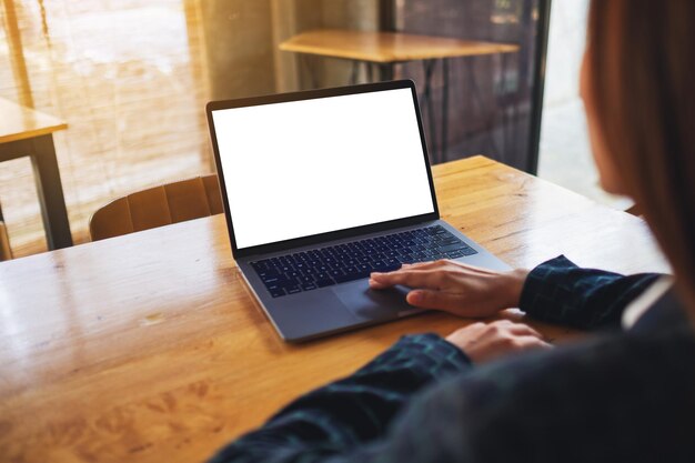 Imagem de maquete de uma mulher usando e tocando o touchpad do computador laptop com a tela do desktop em branco na mesa de madeira