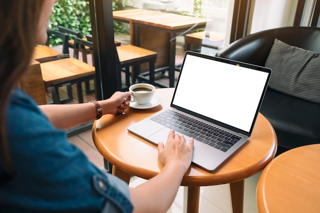 Imagem de maquete de uma mulher usando e tocando o touchpad do laptop com a tela do desktop em branco enquanto bebe café