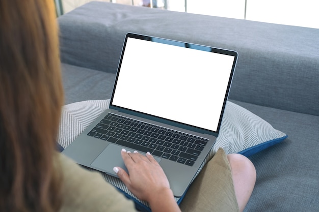 Imagem de maquete de uma mulher usando e tocando o touchpad do laptop com uma tela em branco enquanto está sentada na sala de estar