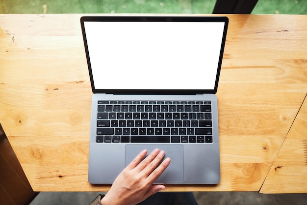 Imagem de maquete de vista superior de uma mulher usando e tocando no touchpad do laptop com a tela do desktop em branco na mesa de madeira