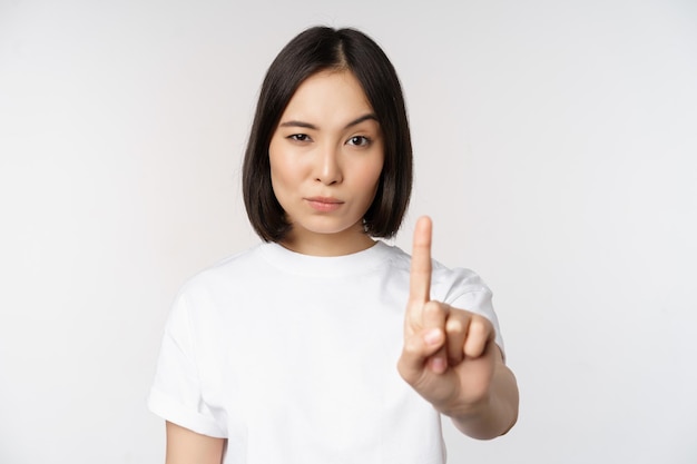 Imagem de menina asiática mostrando parar proibir smth estender um braço para mostrar o gesto proibitivo de pé na camiseta sobre fundo branco