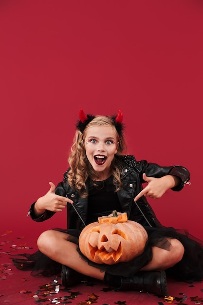 Imagem de menina diabinha chocada e positiva em fantasia de carnaval de halloween