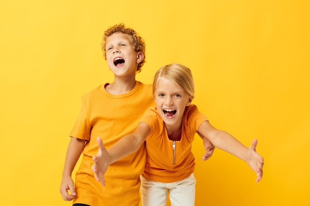 Imagem de menino e menina positivos abraçando entretenimento infantil de moda em fundo colorido inalterado