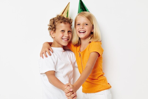 Imagem de menino e menina positivos com tampas em seu fundo de luz de entretenimento de férias de cabeça