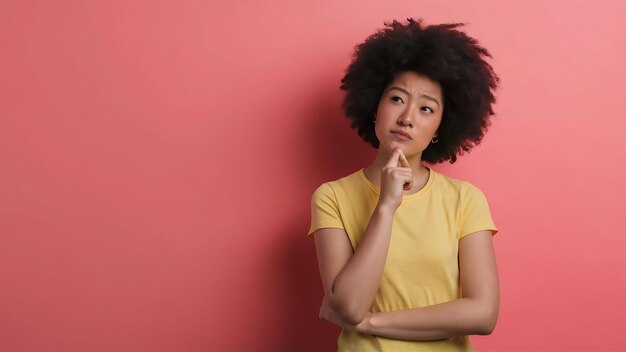 Foto imagem de mulher asiática pensando olhando de lado e ponderando tomando decisão de pé em camisa amarela