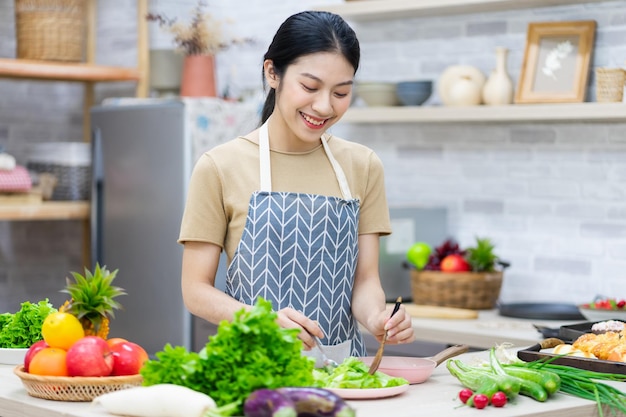 Imagem de mulher asiática preparando salada na cozinha