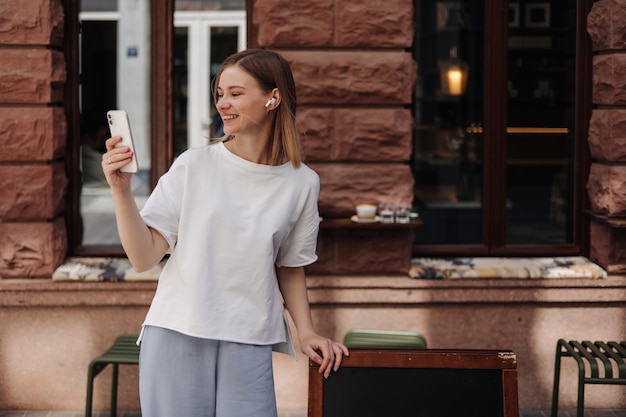 Imagem de mulher atraente sorrindo para smartphone na rua