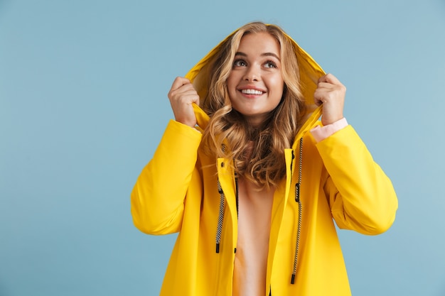 Imagem de mulher caucasiana de 20 anos vestindo capa de chuva amarela sorrindo